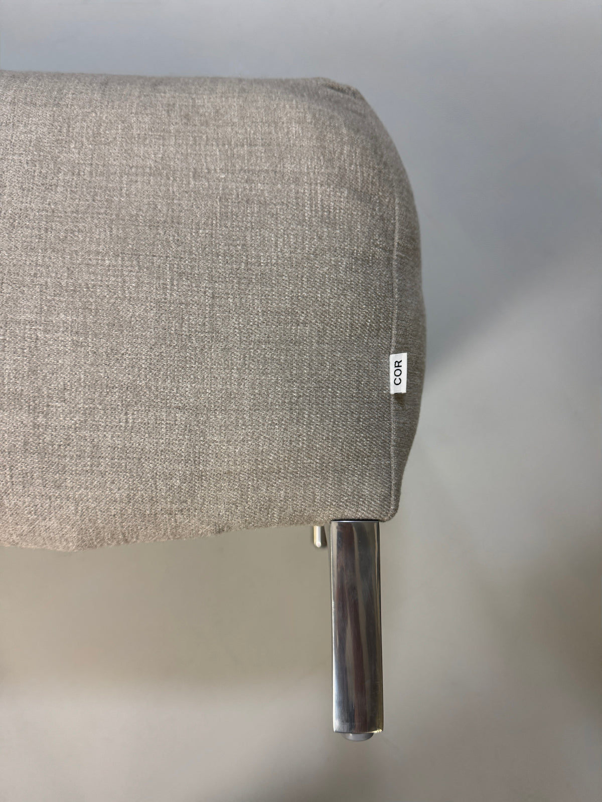 Gebrauchtes graues Stoffsofa mit einem Hocker von COR Modell Avalanche vor einer modernen Wand.