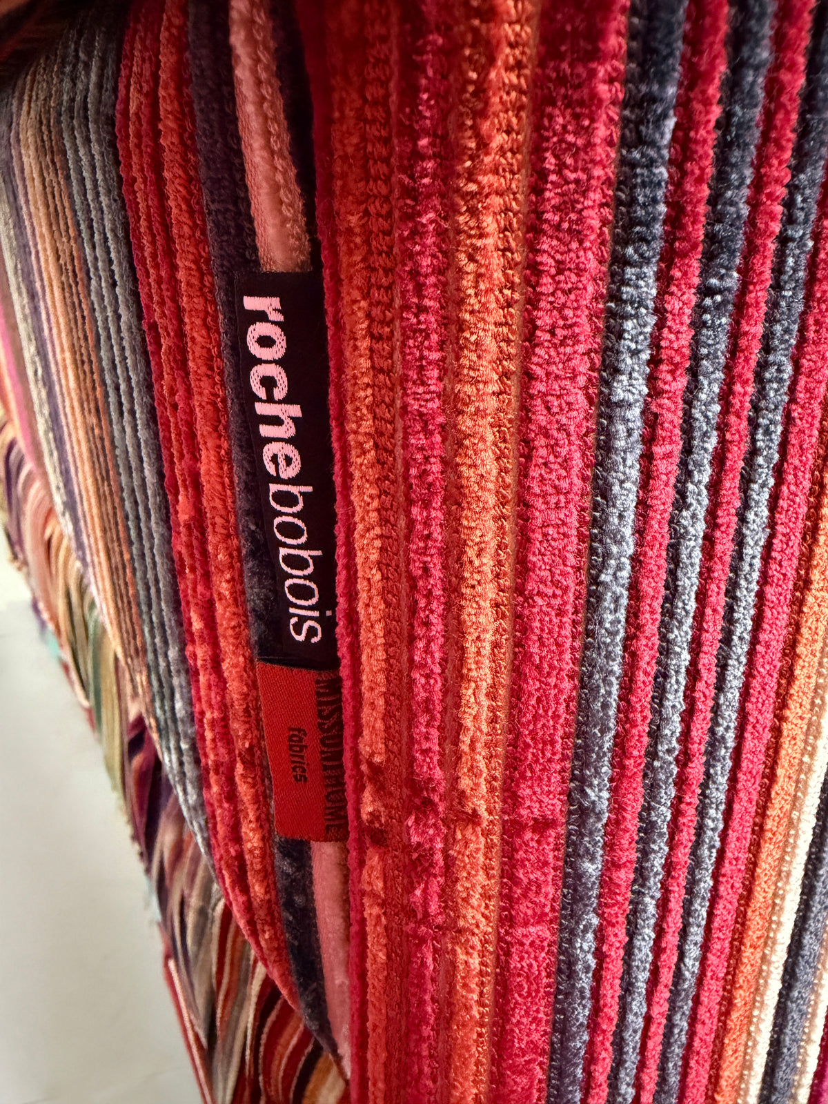 Gebrauchtes buntes Roche Bobois Mah Jong Designer Stoff Sofa vor einer Wand, stilvoll und modern eingerichtet.