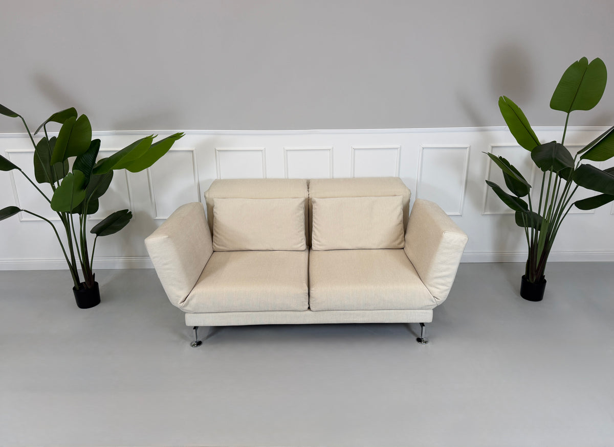 Gebrauchtes beiges Brühl Moule Designer Stoff Sofa vor einer Wand, stilvoll und modern eingerichtet.