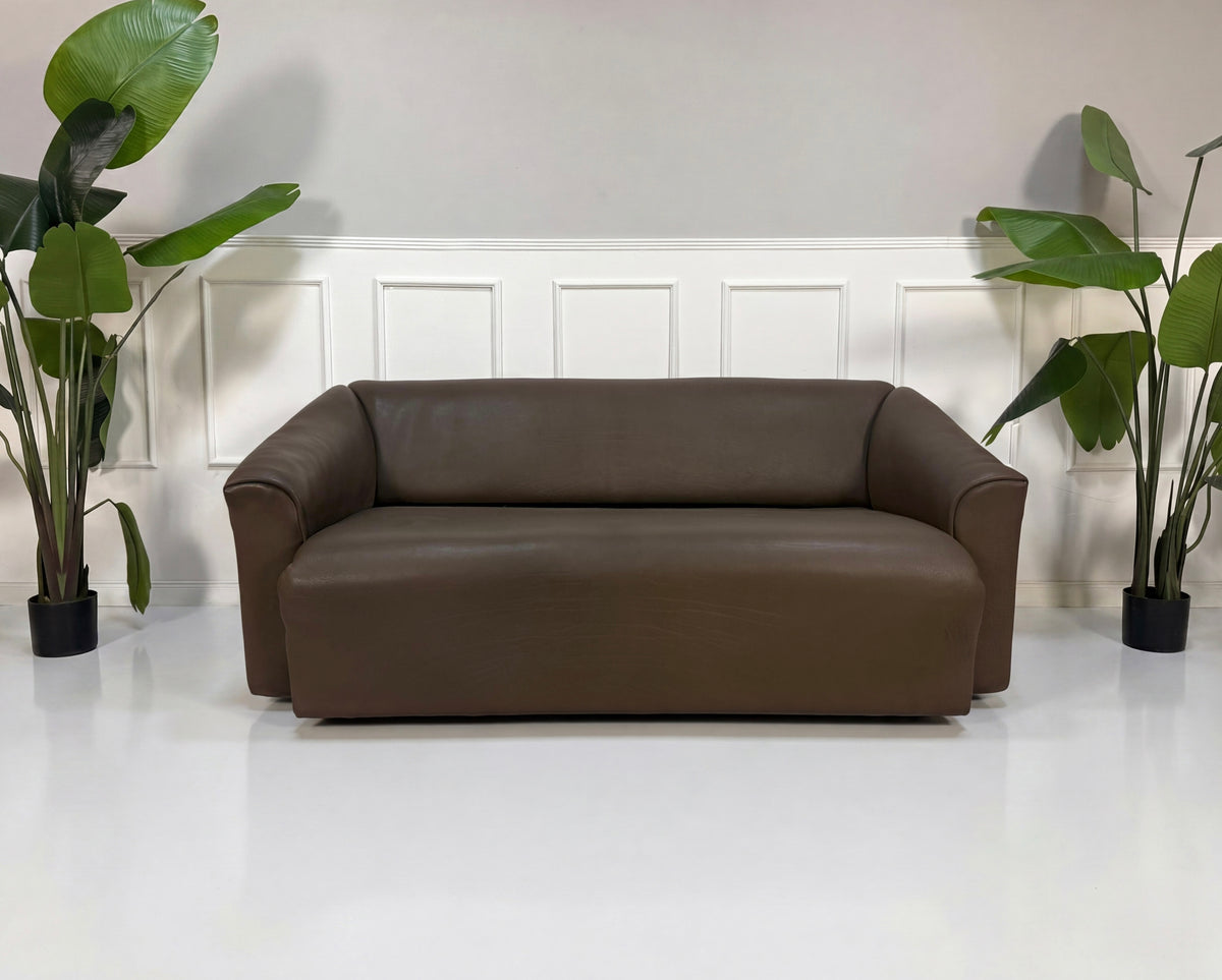 Gebrauchtes braunes De Sede DS 47 Designer Leder Sofa vor einer Wand, stilvoll und modern eingerichtet.