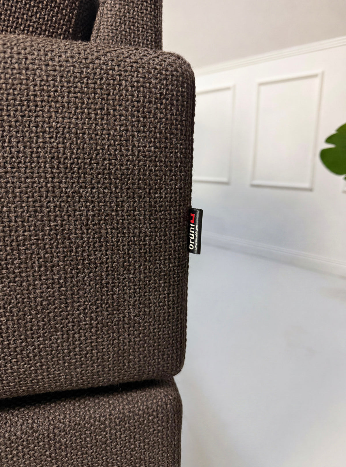 Gebrauchtes braunes Brühl Alba Designer Stoff Ecksofa vor einer Wand, stilvoll und modern eingerichtet.