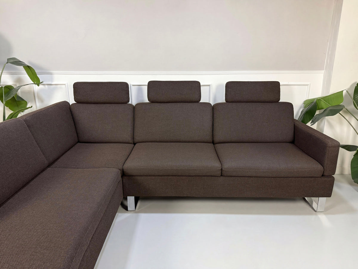 Gebrauchtes braunes Brühl Alba Designer Stoff Ecksofa vor einer Wand, stilvoll und modern eingerichtet.