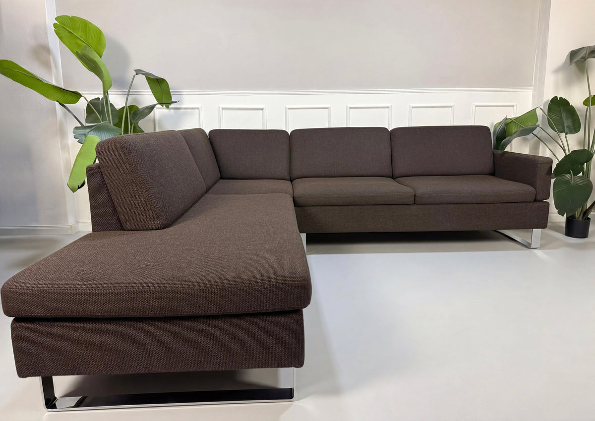 Gebrauchtes braunes Brühl Alba Designer Stoff Ecksofa vor einer Wand, stilvoll und modern eingerichtet.