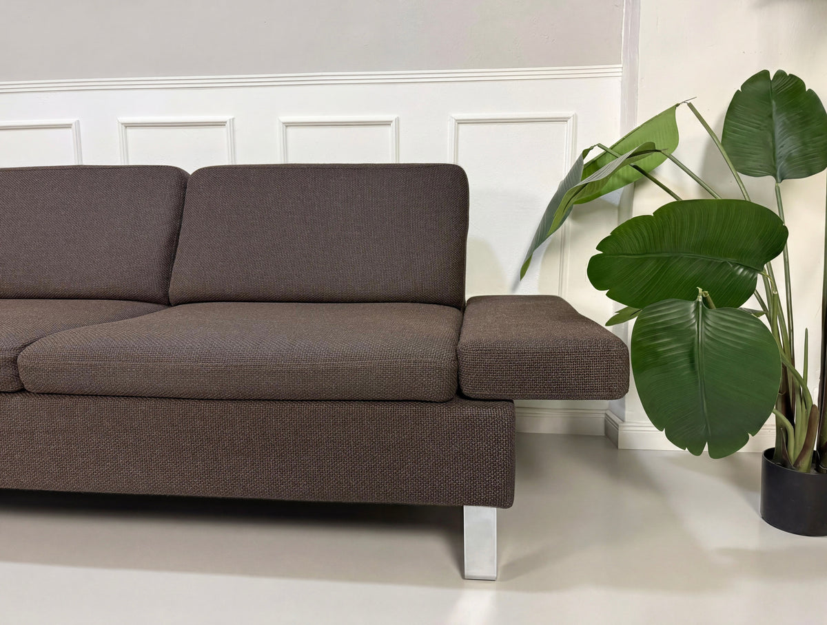 Gebrauchtes braunes Brühl Alba Designer Stoff Ecksofa vor einer Wand, stilvoll und modern eingerichtet.