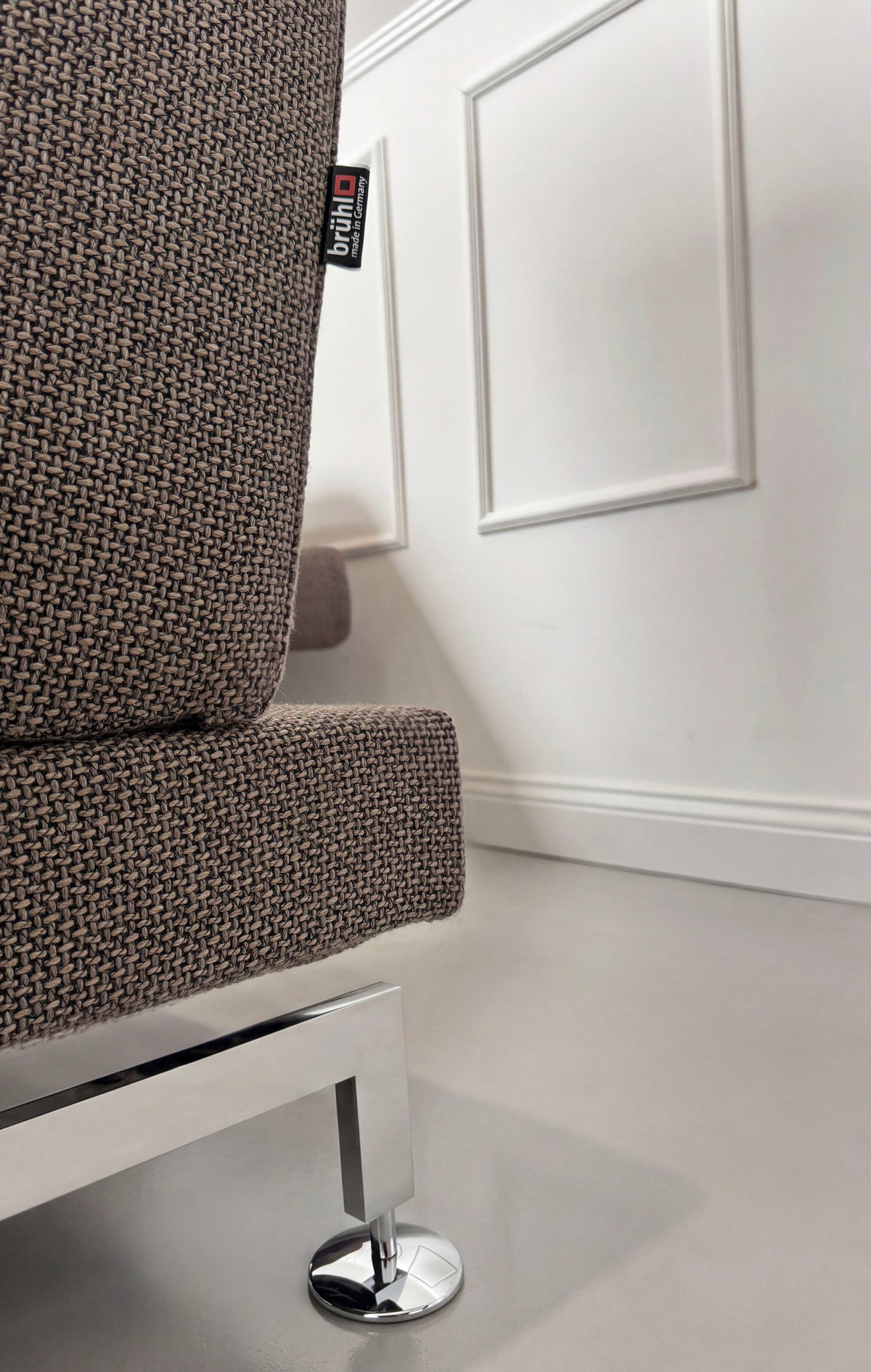 Gebrauchtes braun-graues Brühl Moule Designer Stoff Ecksofa vor einer Wand, stilvoll und modern eingerichtet.