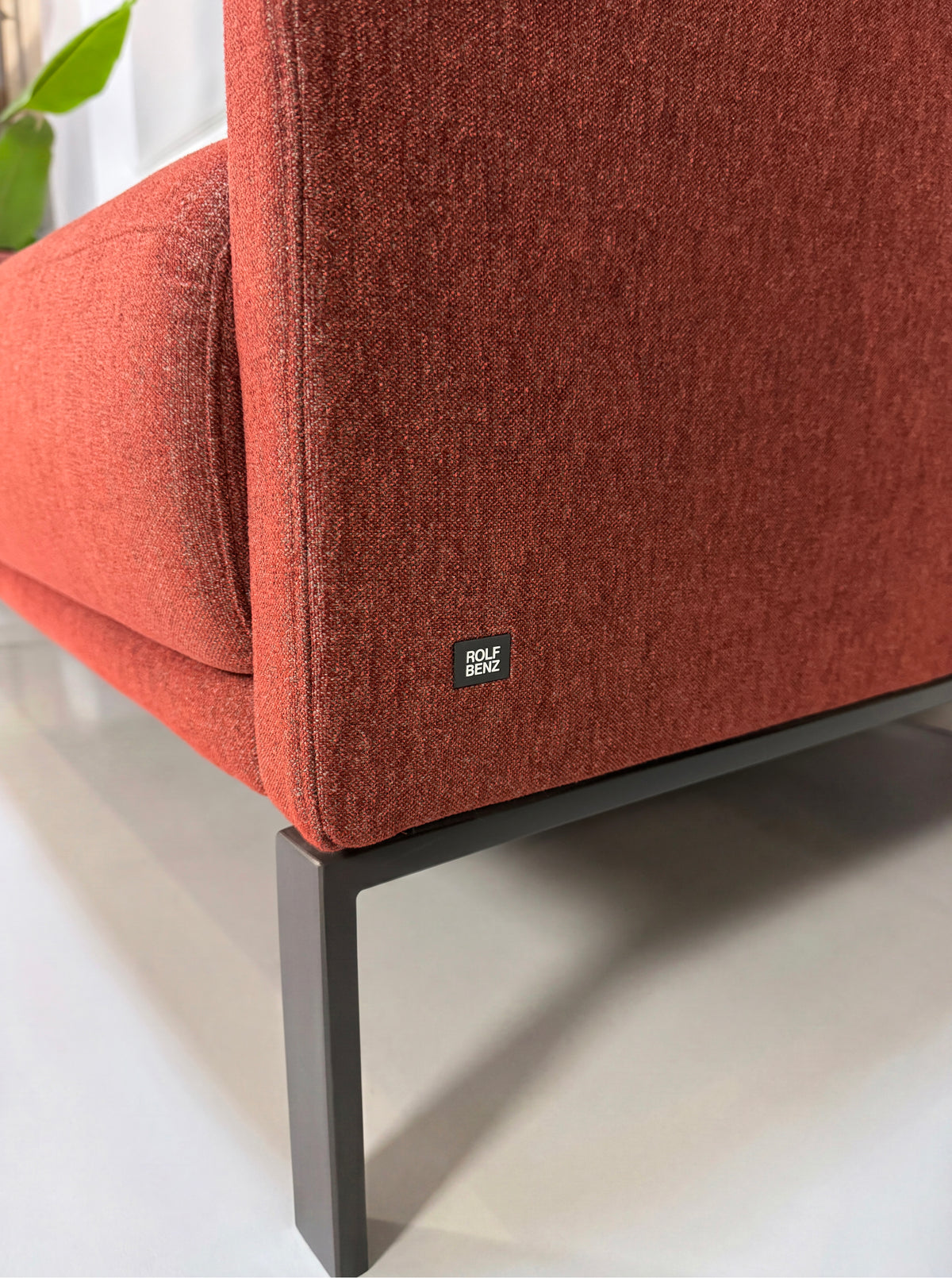 Gebrauchtes rotes Rolf Benz Cara Designer Stoff Sofa vor einer Wand, stilvoll und modern eingerichtet.