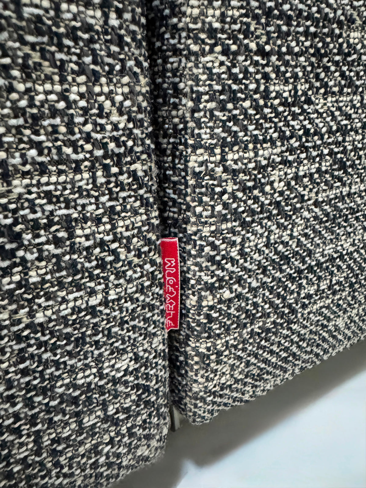 Gebrauchtes graues Flexform Groundpiece Designer Stoff Sofa vor einer Wand, stilvoll und modern eingerichtet.