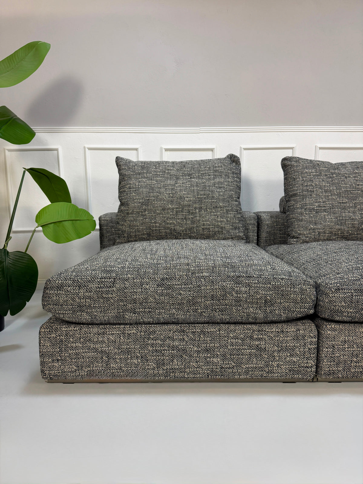 Gebrauchtes graues Flexform Groundpiece Designer Stoff Sofa vor einer Wand, stilvoll und modern eingerichtet.