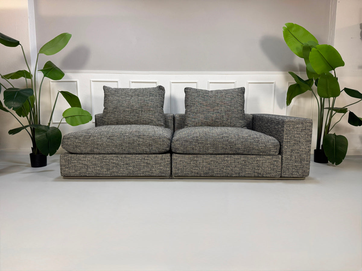 Gebrauchtes graues Flexform Groundpiece Designer Stoff Sofa vor einer Wand, stilvoll und modern eingerichtet.