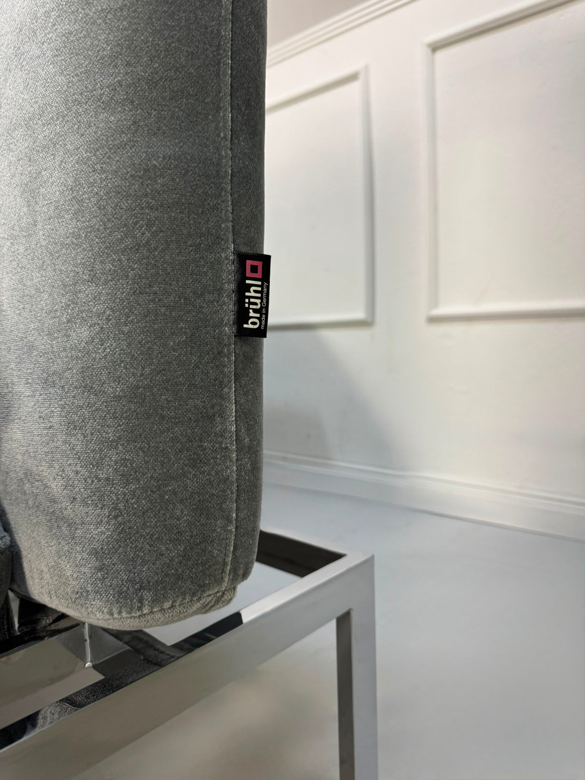 Gebrauchtes graues Brühl Roro medium Designer Stoff Sofa vor einer Wand, stilvoll und modern eingerichtet.