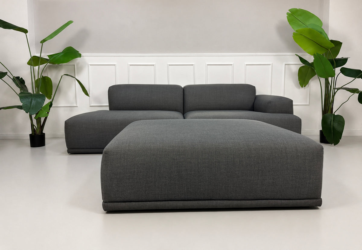 Gebrauchtes graues Muuto Connect Designer Stoff Ecksofa vor einer Wand, stilvoll und modern eingerichtet.