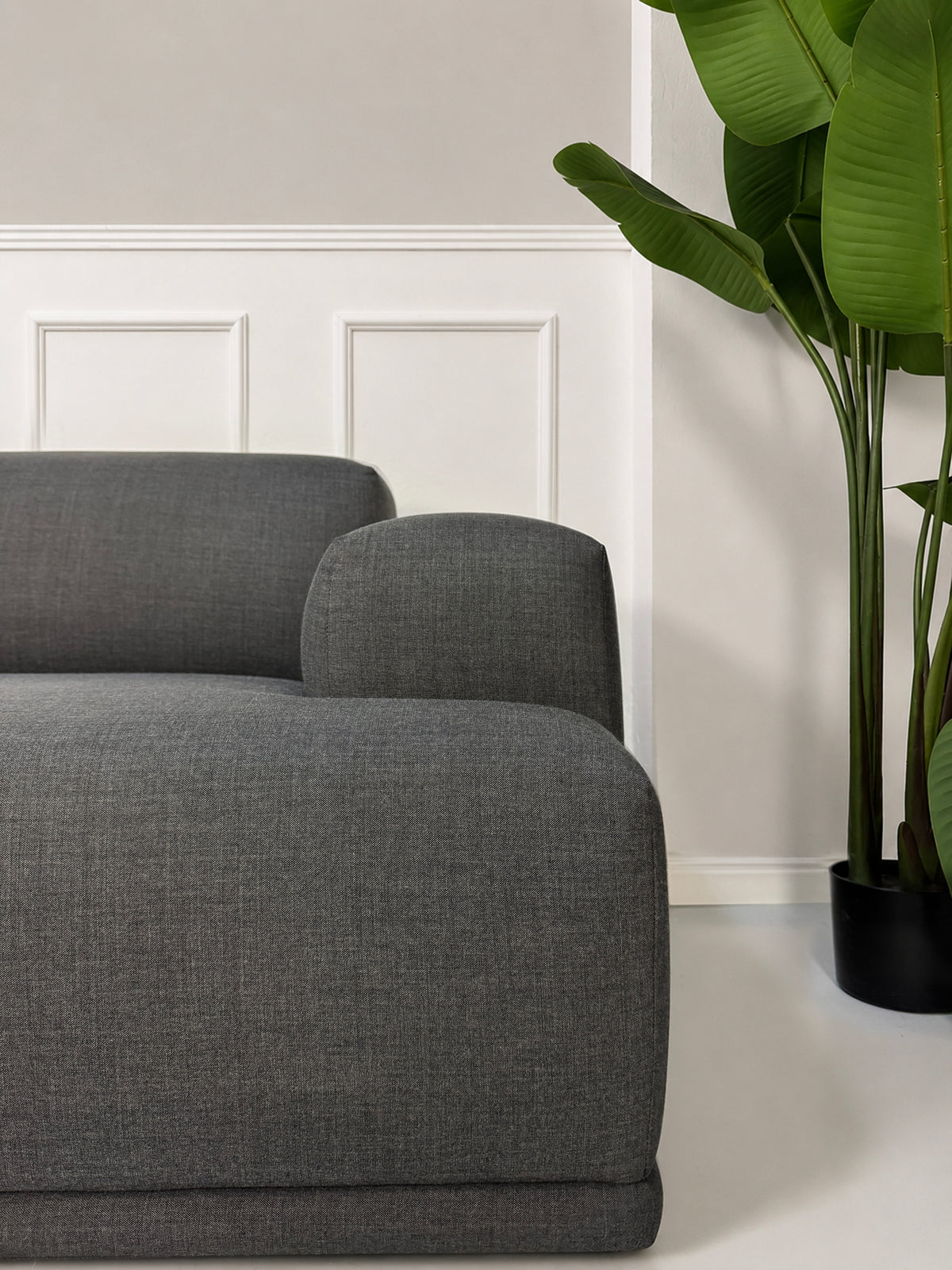 Gebrauchtes graues Muuto Connect Designer Stoff Ecksofa vor einer Wand, stilvoll und modern eingerichtet.