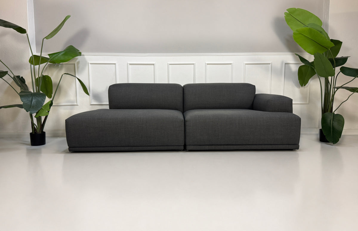 Gebrauchtes graues Muuto Connect Designer Stoff Ecksofa vor einer Wand, stilvoll und modern eingerichtet.
