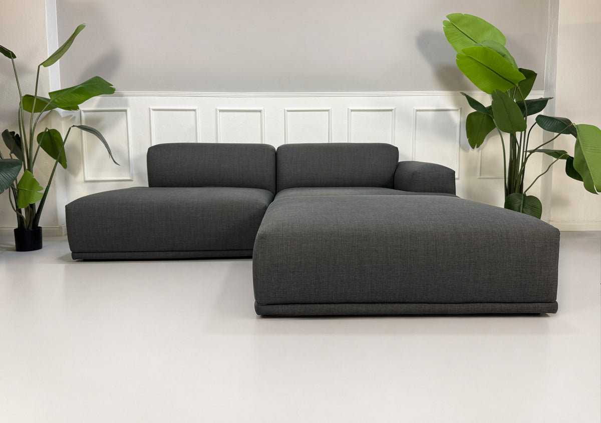 Gebrauchtes graues Muuto Connect Designer Stoff Ecksofa vor einer Wand, stilvoll und modern eingerichtet.