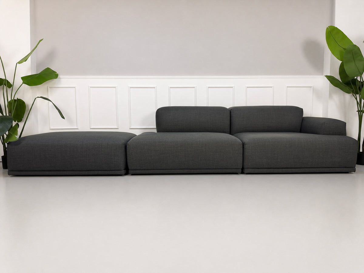 Gebrauchtes graues Muuto Connect Designer Stoff Ecksofa vor einer Wand, stilvoll und modern eingerichtet.