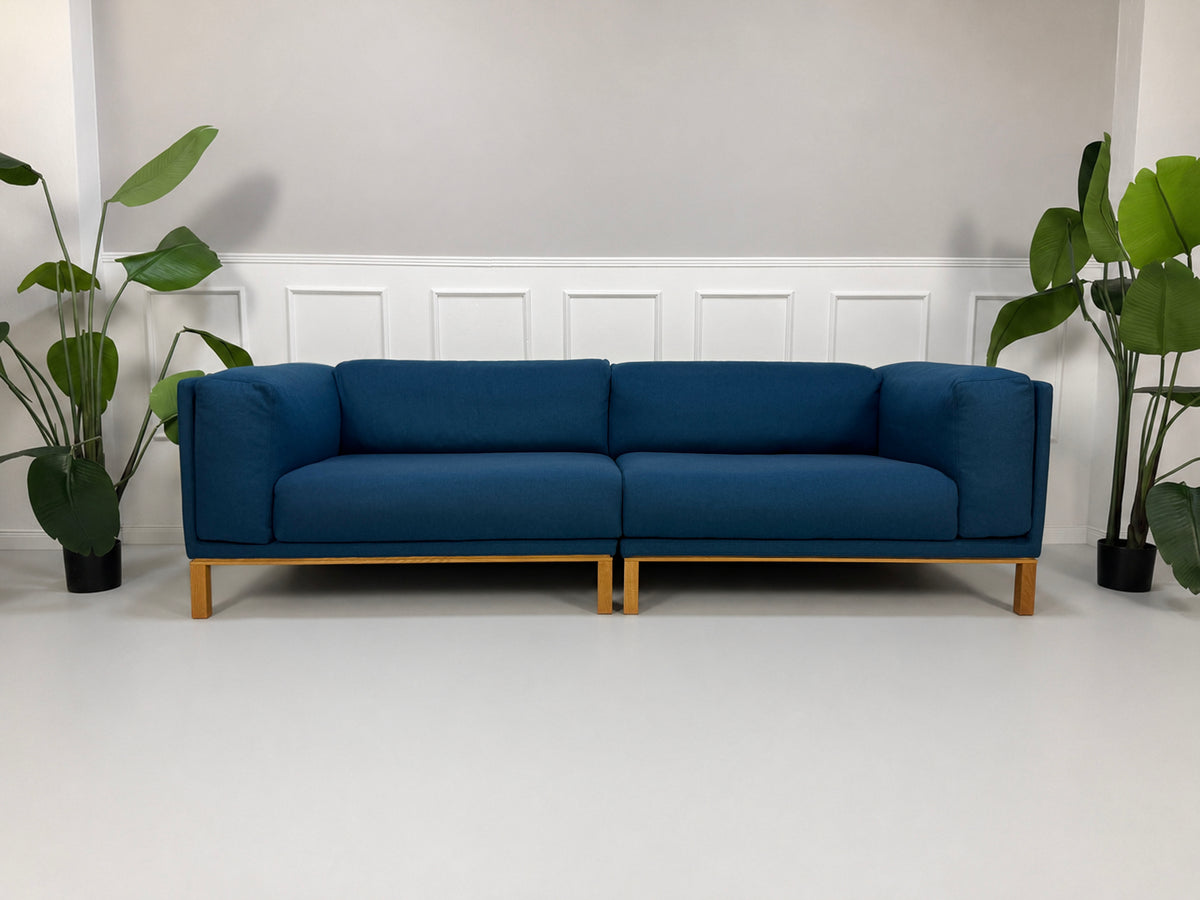 Gebrauchtes blaues Bolia Cosy Designer Stoff Sofa vor einer Wand, stilvoll und modern eingerichtet.