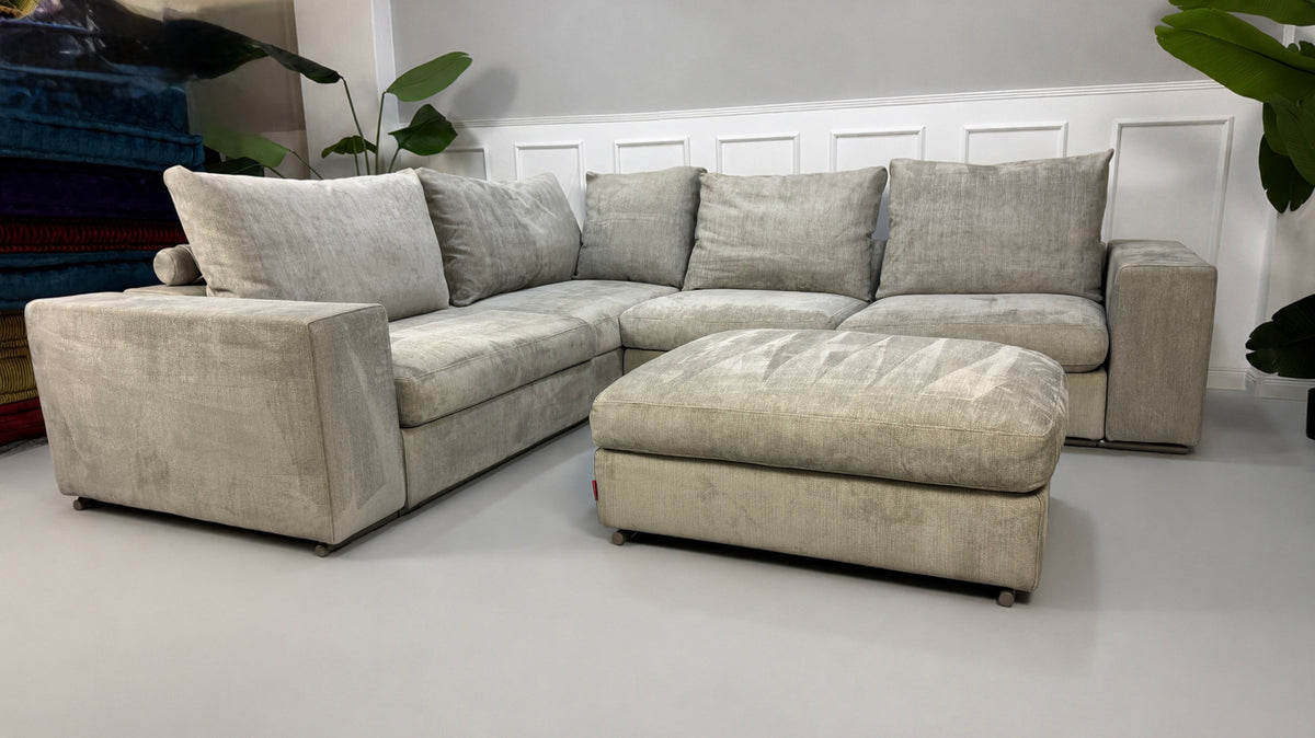 Gebrauchtes graues Flexform Groundpiece Designer Stoff Sofa vor einer Wand, stilvoll und modern eingerichtet.