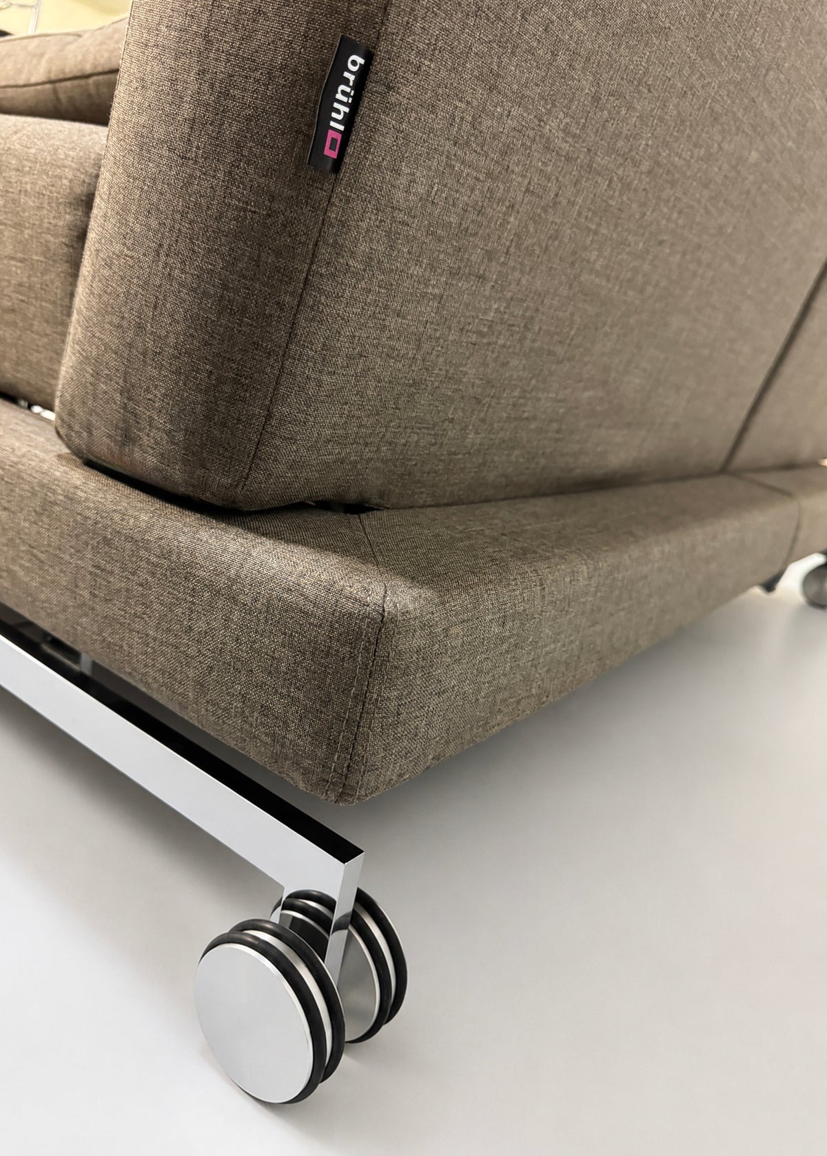 Gebrauchtes braunes Brühl Moule Designer Stoff Sofa vor einer Wand, stilvoll und modern eingerichtet.