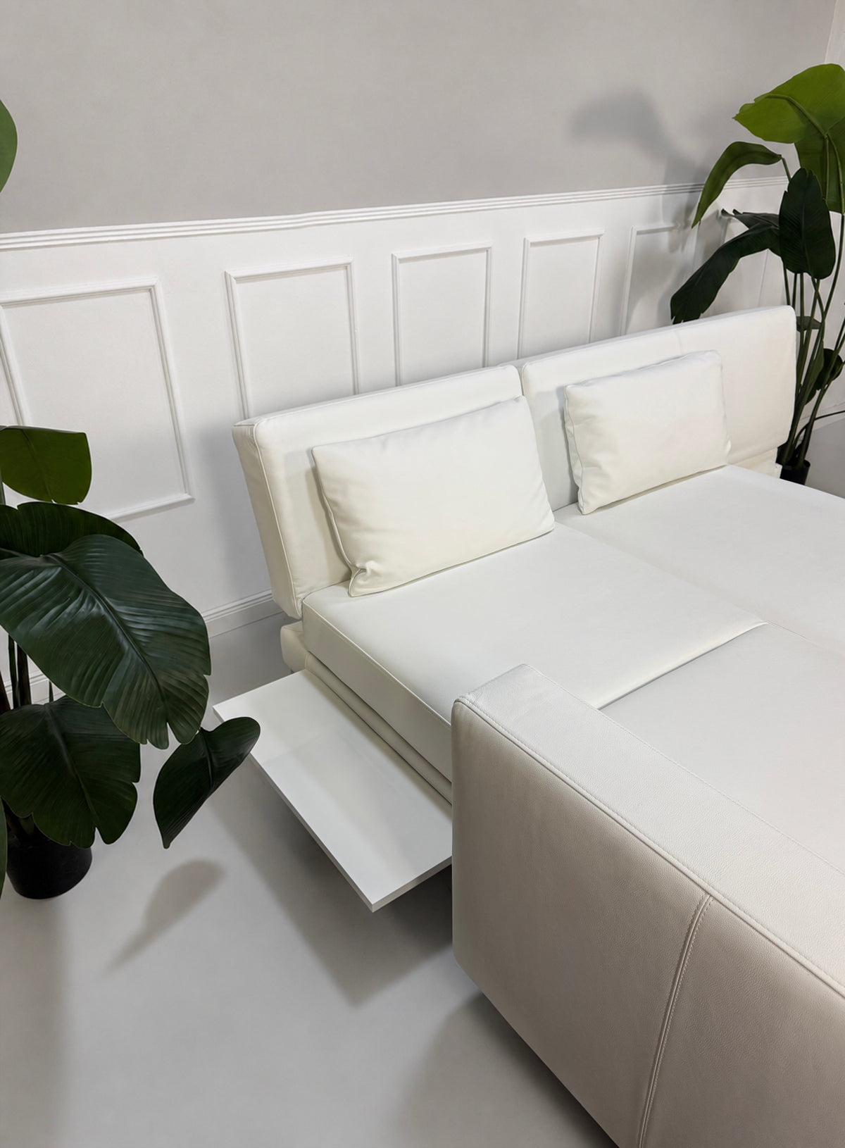 Gebrauchtes weißes Brühl Fourtwo Designer Leder Ecksofa vor einer Wand, stilvoll und modern eingerichtet.