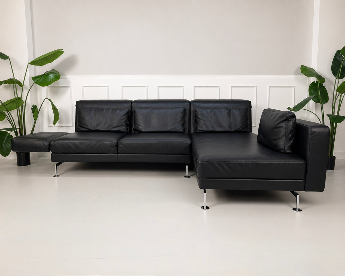 Gebrauchtes schwarzes Brühl Moule Designer Leder Sofa vor einer Wand, stilvoll und modern eingerichtet.