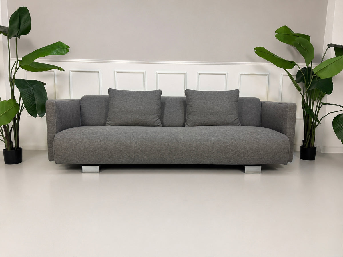 Gebrauchtes graues Rolf Benz 6300 Designer Stoff Sofa vor einer Wand, stilvoll und modern eingerichtet.