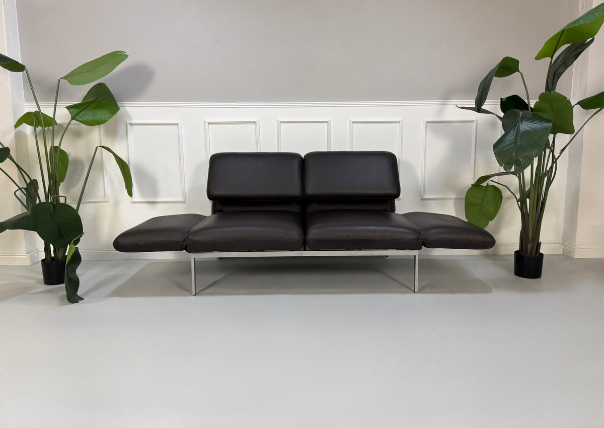 Gebrauchte braune Brühl Roro Designer Leder Sofas vor einer Wand, stilvoll und modern eingerichtet.