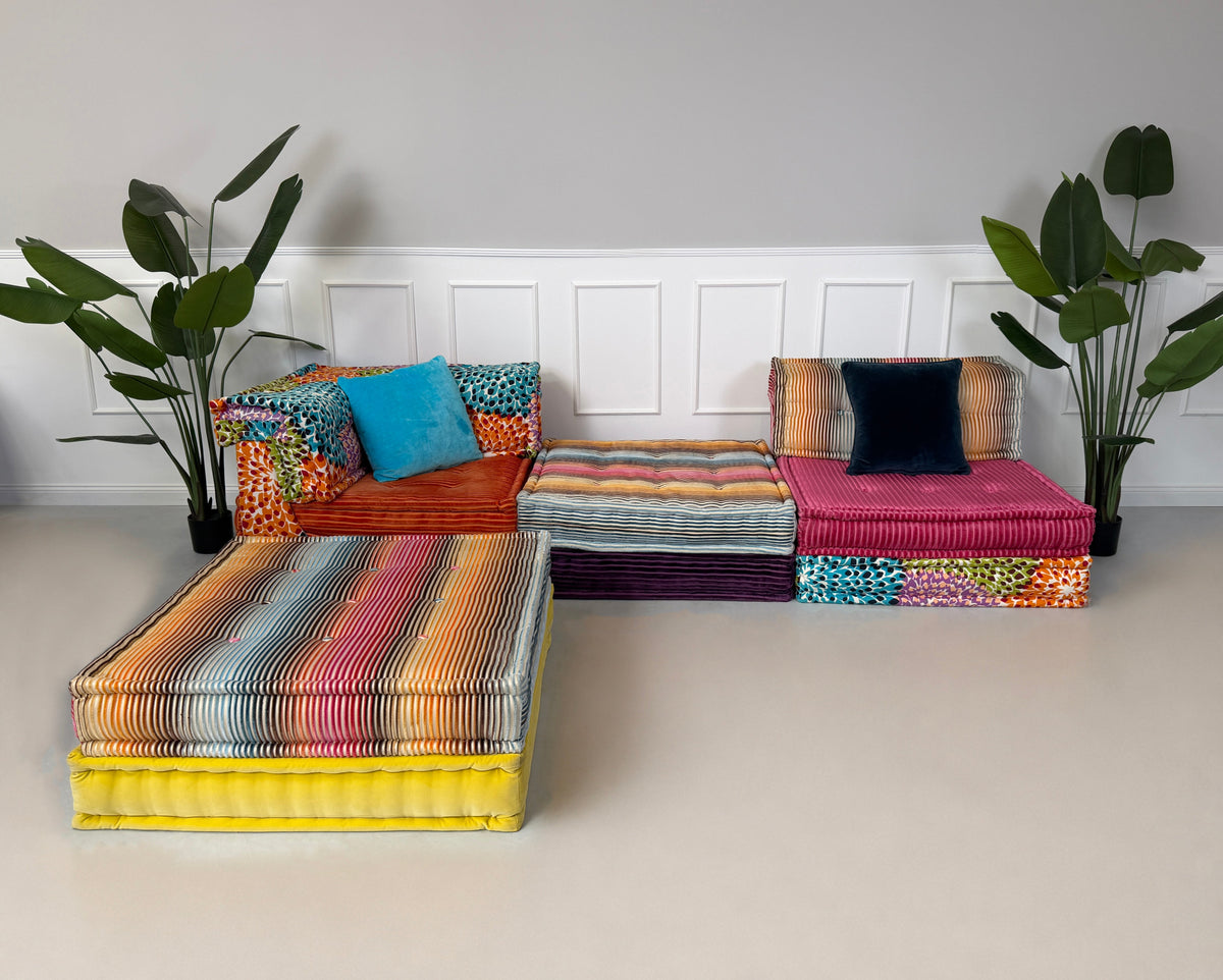 Gebrauchtes buntes Roche Bobois Mah Jong Designer Stoff Ecksofa vor einer Wand, stilvoll und modern eingerichtet.