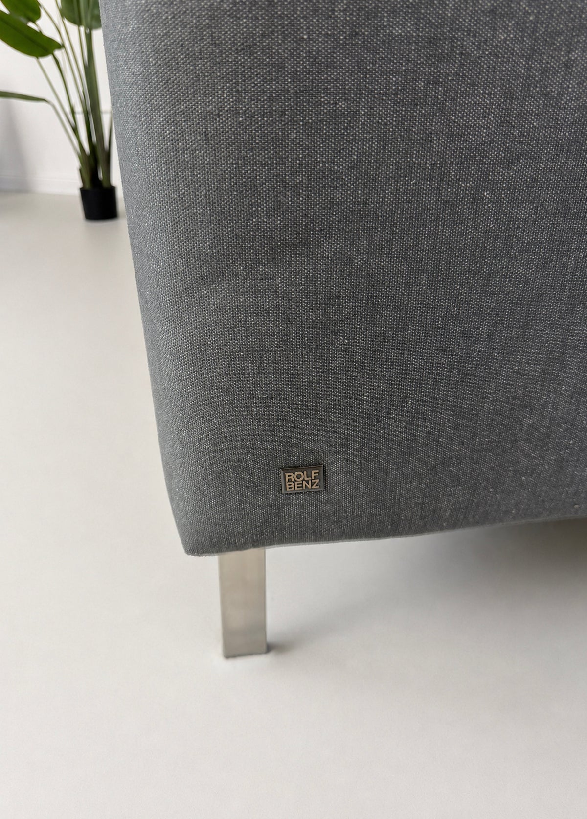 Gebrauchtes graues Rolf Benz 318 Linea Designer Stoff Sofa mit Hocker vor einer Wand, stilvoll und modern eingerichtet.