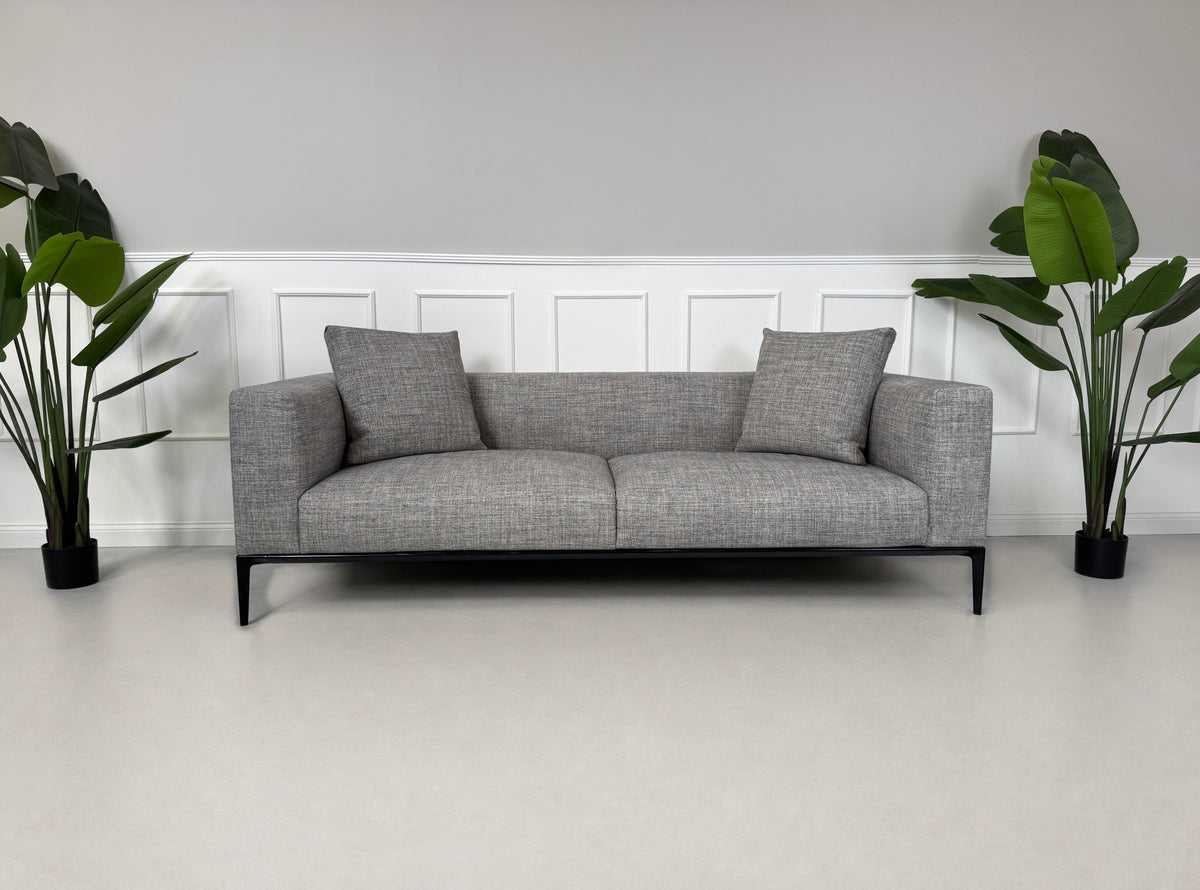 Gebrauchtes graues Walter Knoll Jaan Living Designer Stoff Sofa mit Hocker vor einer Wand, stilvoll und modern eingerichtet.