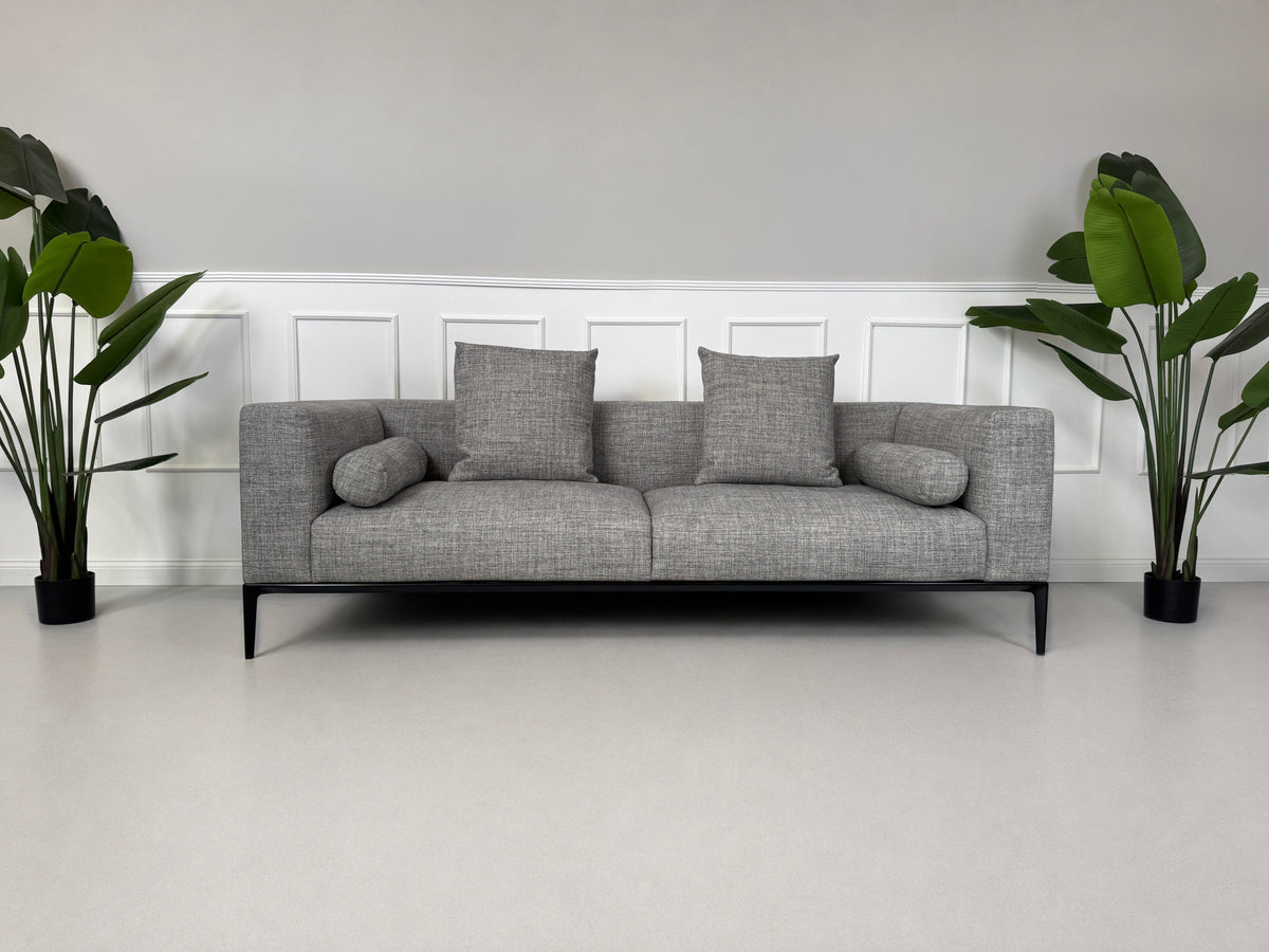 Gebrauchtes graues Walter Knoll Jaan Living Designer Stoff Sofa mit Hocker vor einer Wand, stilvoll und modern eingerichtet.