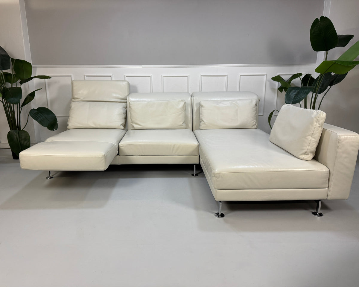 Gebrauchtes weißes Brühl Moule Designer Leder Sofa vor einer Wand, stilvoll und modern eingerichtet.