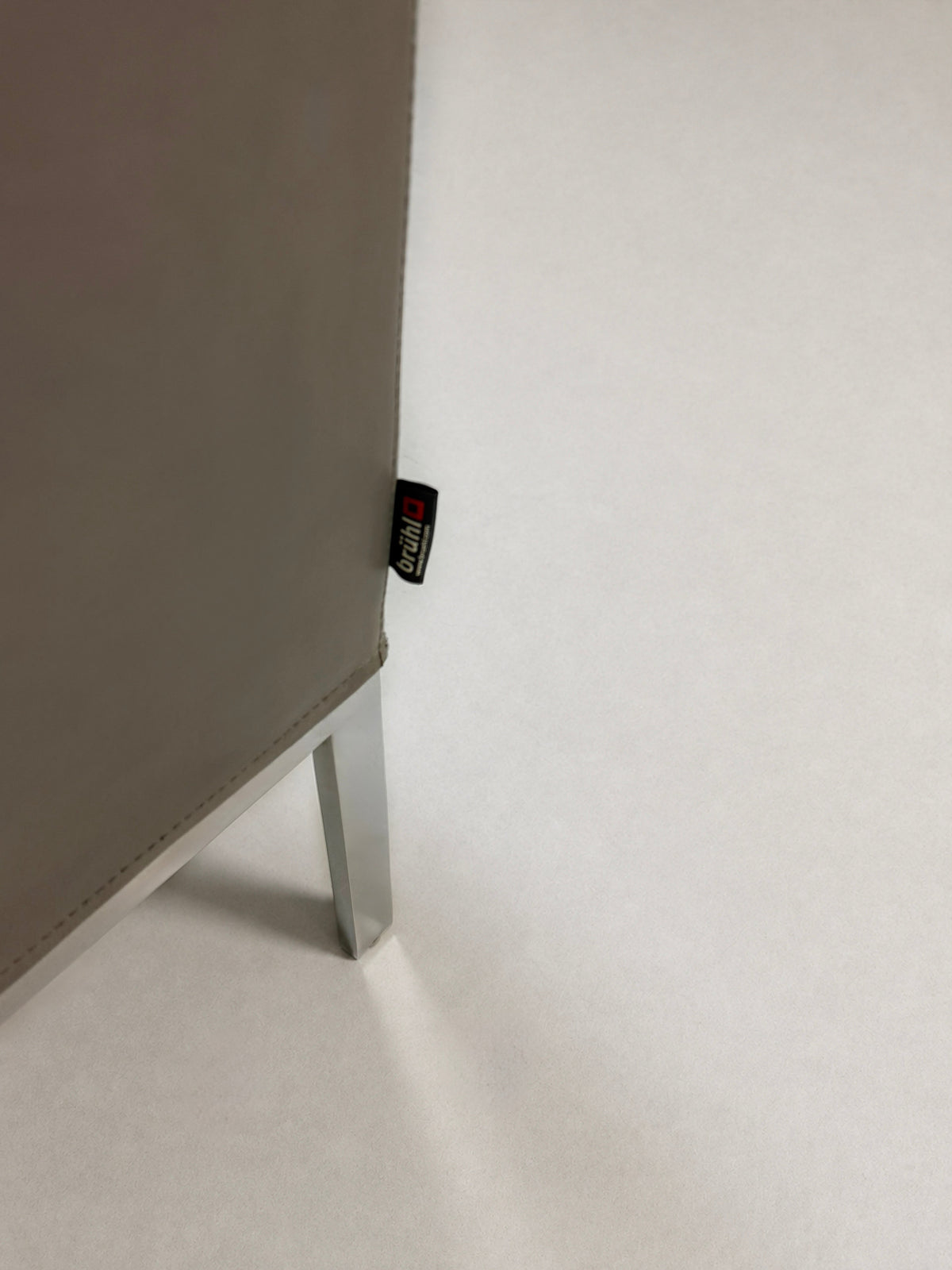 Gebrauchter grauer Brühl Randolph Designer Leder Sessel vor einer Wand, stilvoll und modern eingerichtet.