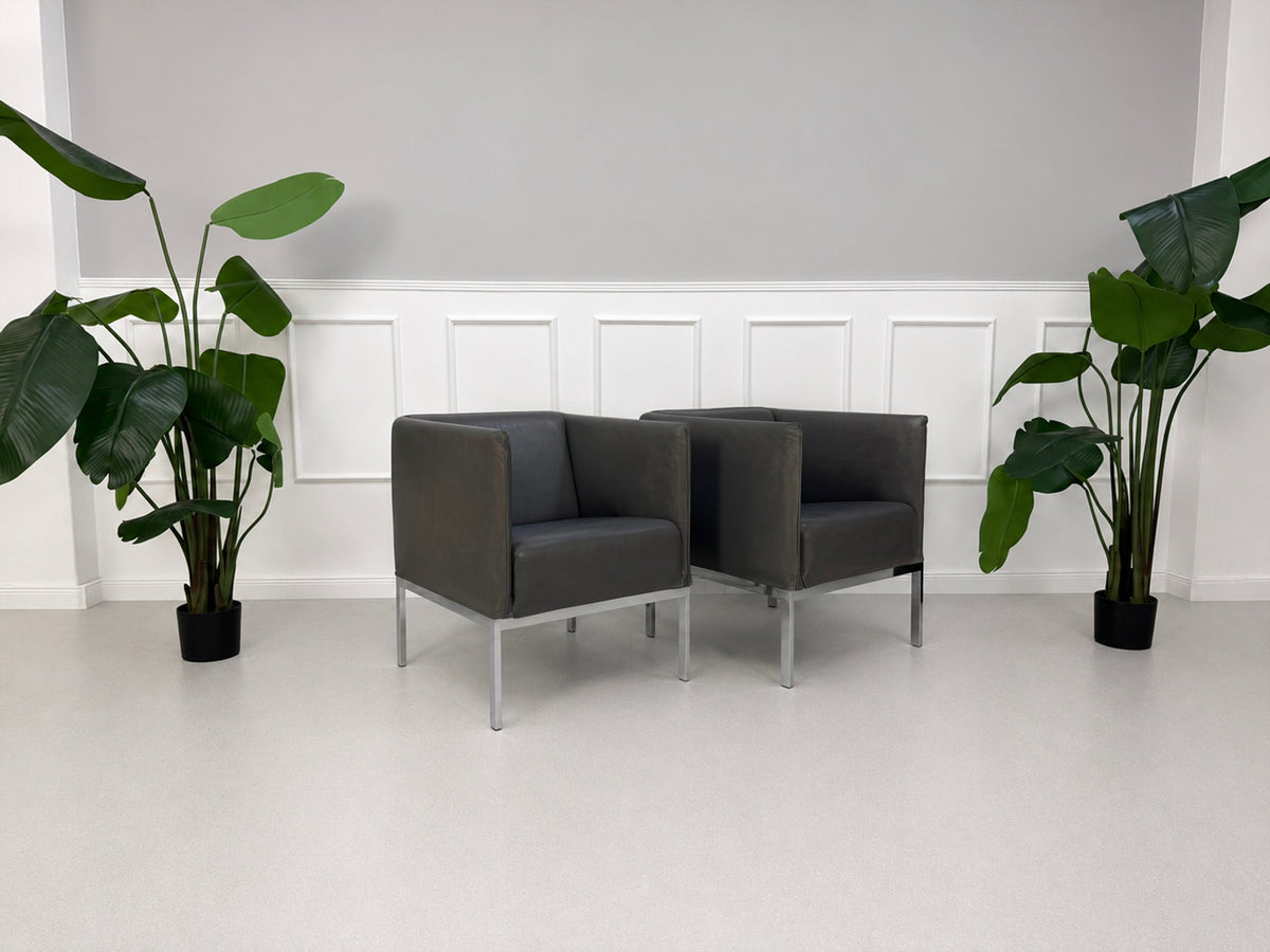 Gebrauchter grauer Brühl Randolph Designer Leder Sessel vor einer Wand, stilvoll und modern eingerichtet.