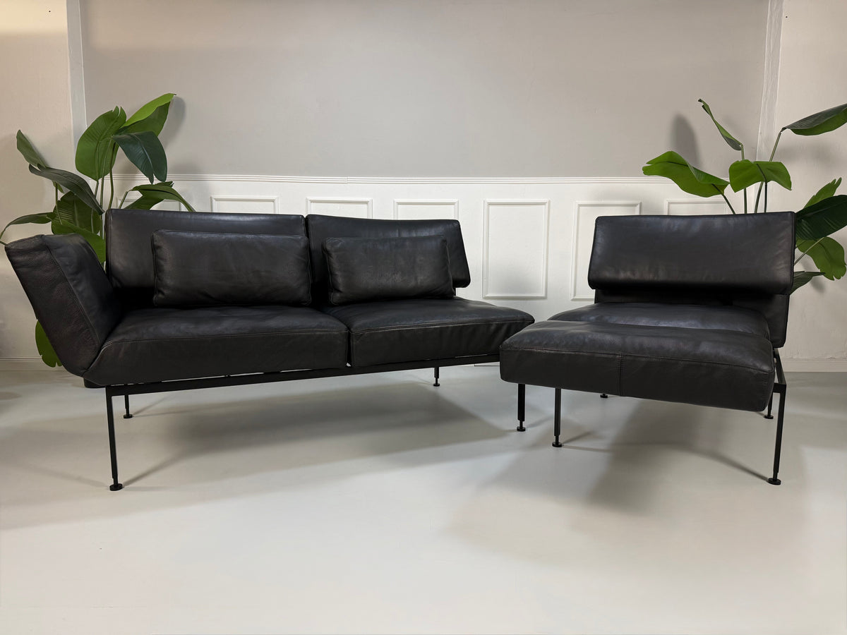 Gebrauchtes schwarzes Brühl Roro Soft Designer Leder Sofa vor einer Wand, stilvoll und modern eingerichtet.