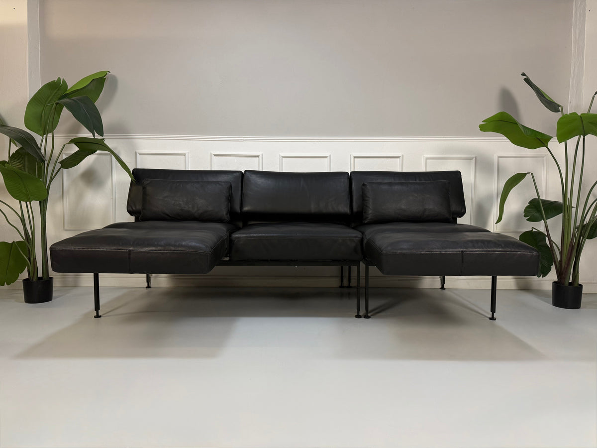 Gebrauchtes schwarzes Brühl Roro Soft Designer Leder Sofa vor einer Wand, stilvoll und modern eingerichtet.