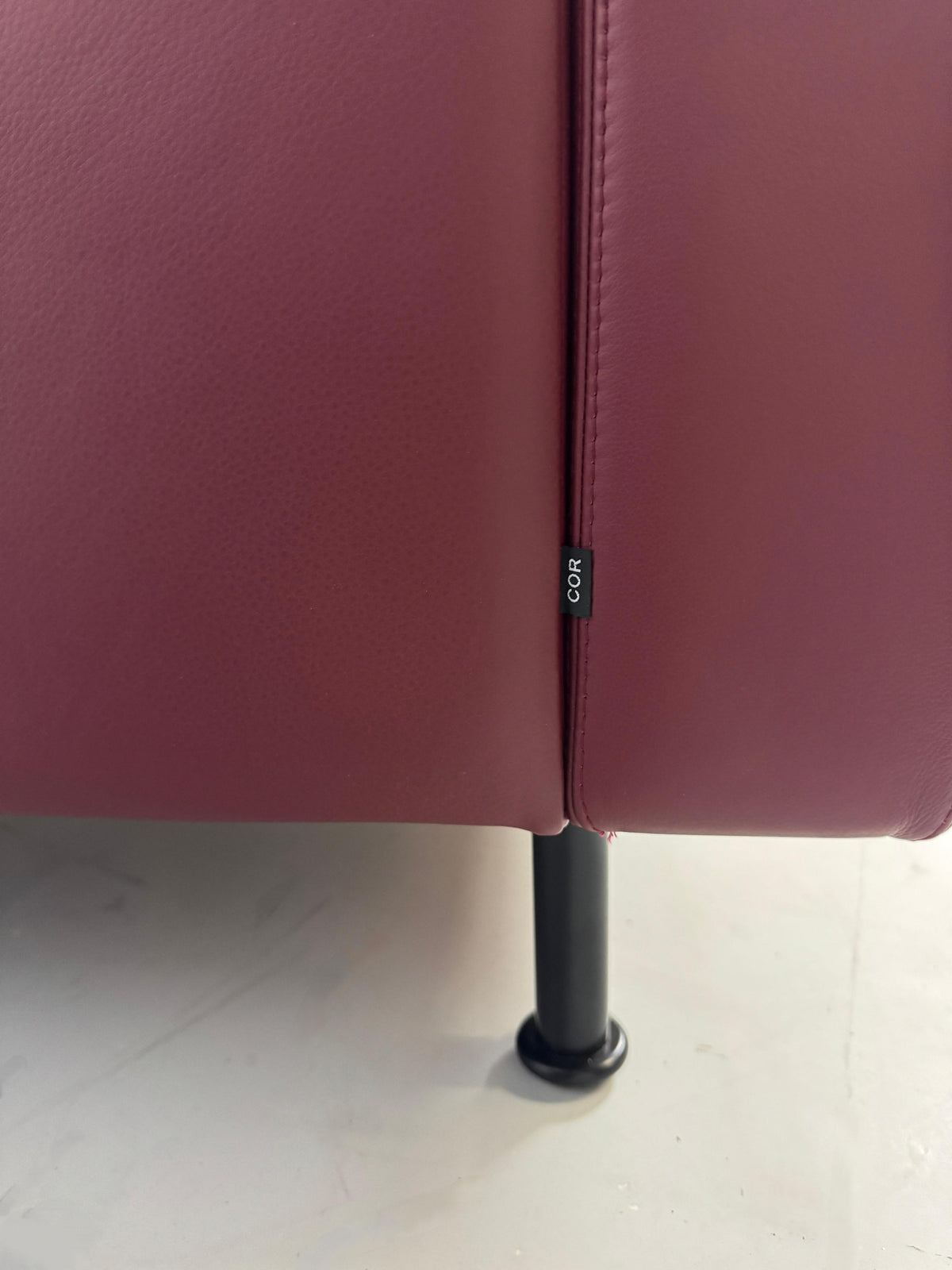 Gebrauchtes rotes COR Conseta Designer Leder Sofa vor einer Wand, stilvoll und modern eingerichtet.