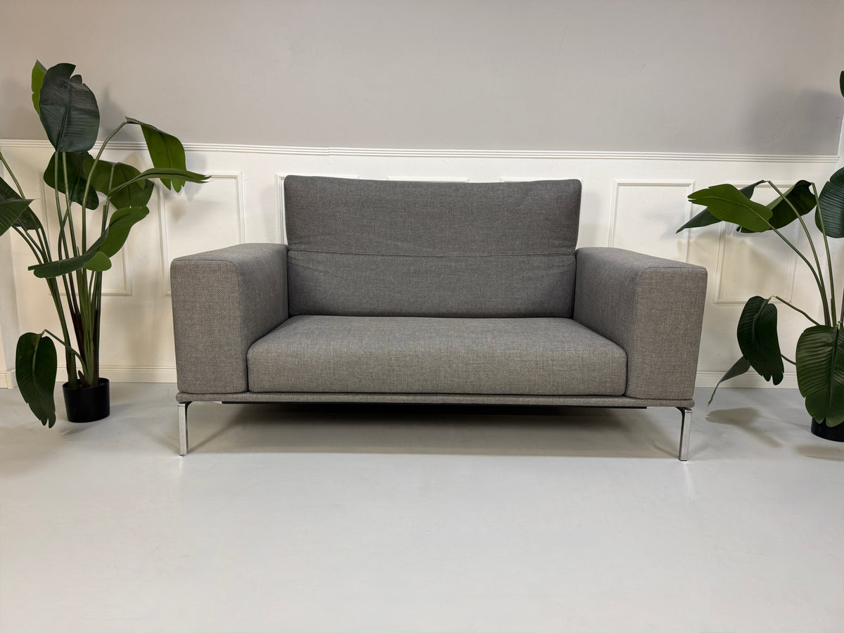 Gebrauchtes graues Cassina Moov Zweisitzer Designer Stoff Sofa vor einer Wand, stilvoll und modern eingerichtet.