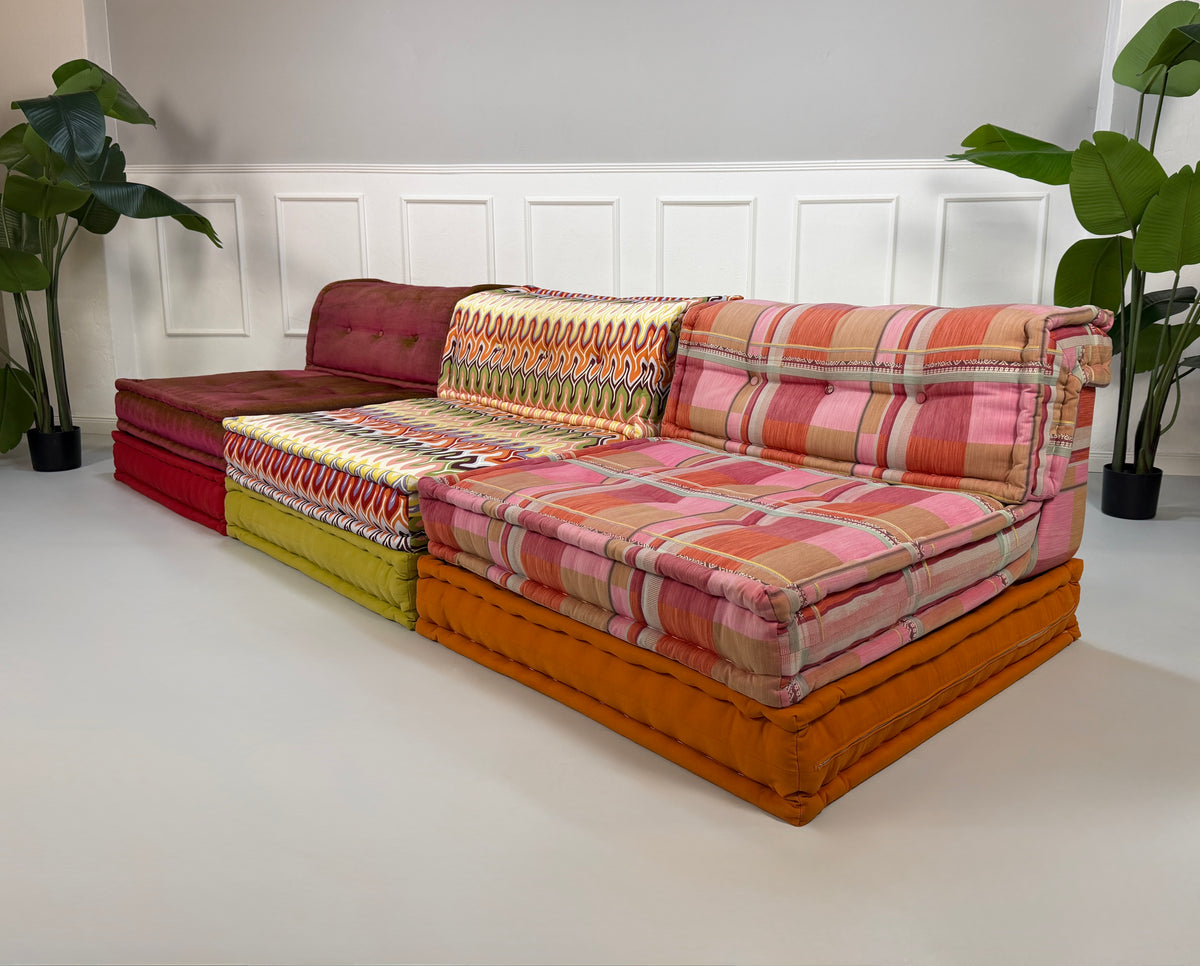 Gebrauchtes buntes Roche Bobois Mah Jong Designer Stoff Sofa vor einer Wand, stilvoll und modern eingerichtet.