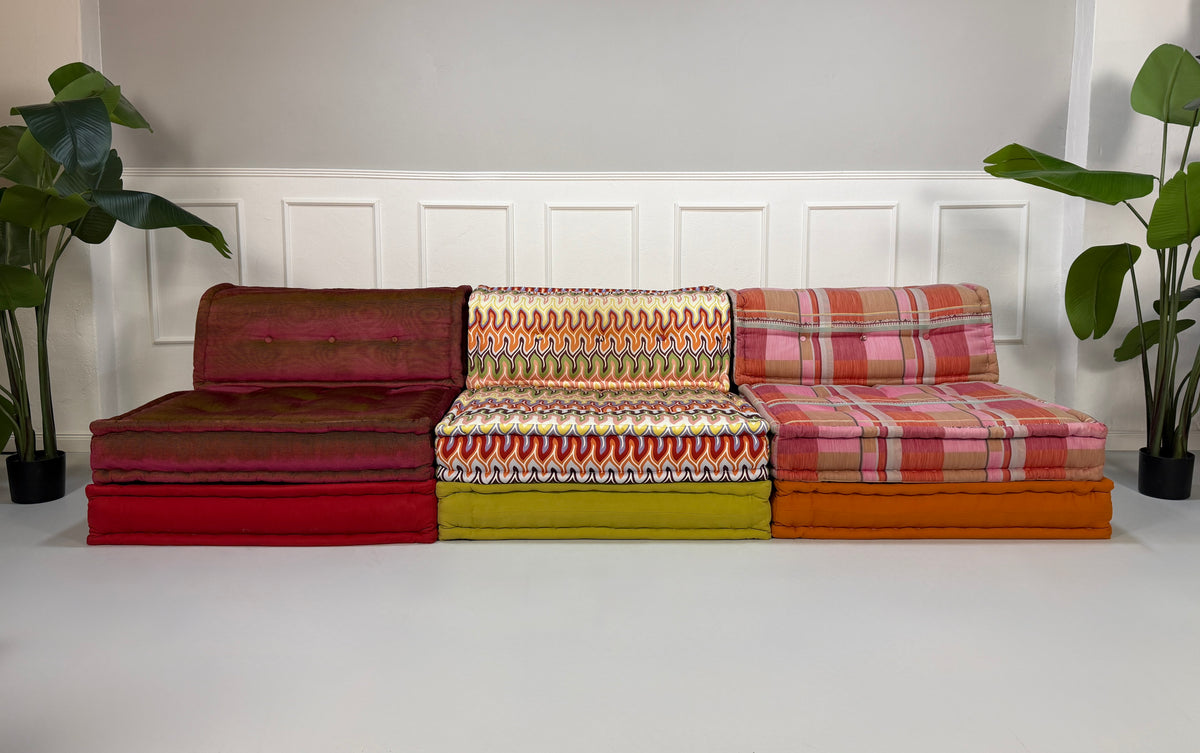 Gebrauchtes buntes Roche Bobois Mah Jong Designer Stoff Sofa vor einer Wand, stilvoll und modern eingerichtet.