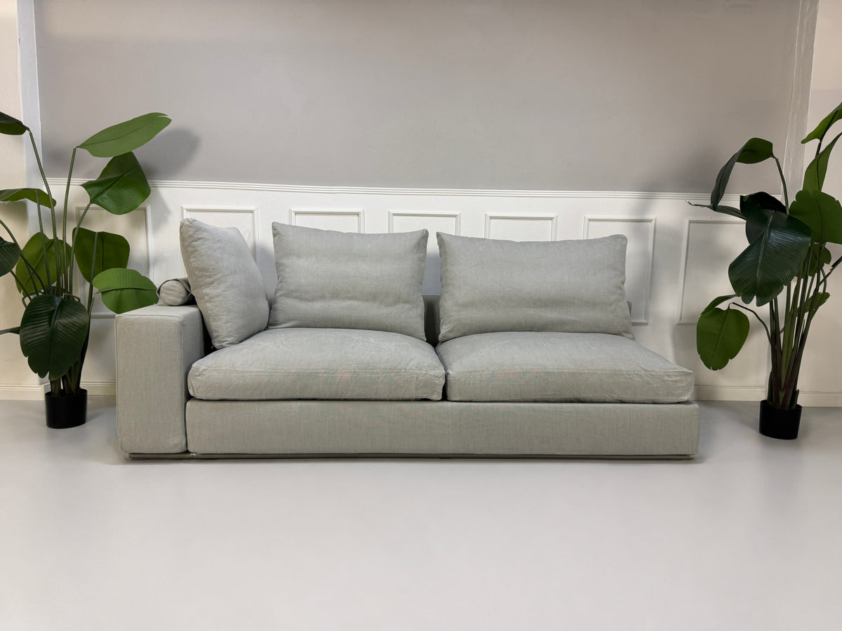 Gebrauchtes graues Flexform Groundpiece Designer Stoff Sofa vor einer Wand, stilvoll und modern eingerichtet.