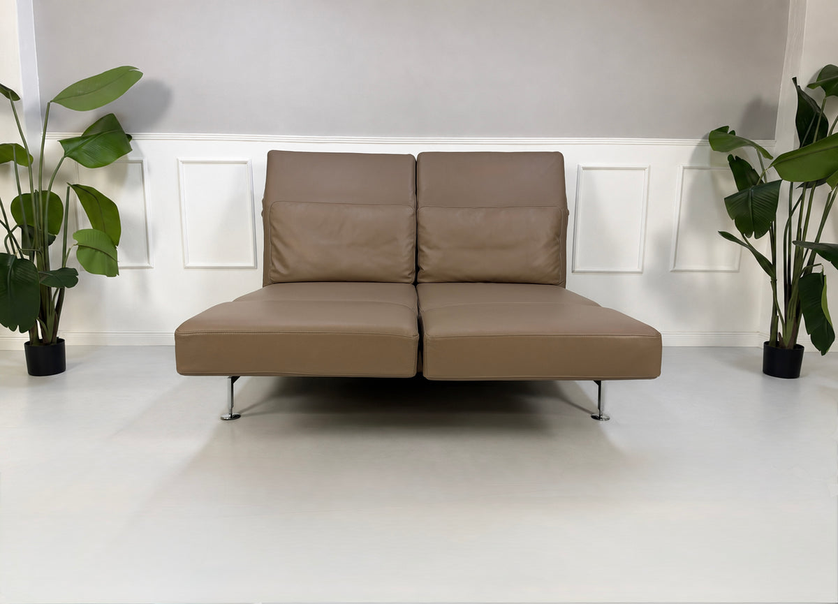 Gebrauchtes braunes Brühl Moule Medium Designer Leder Sofa vor einer Wand, stilvoll und modern eingerichtet.